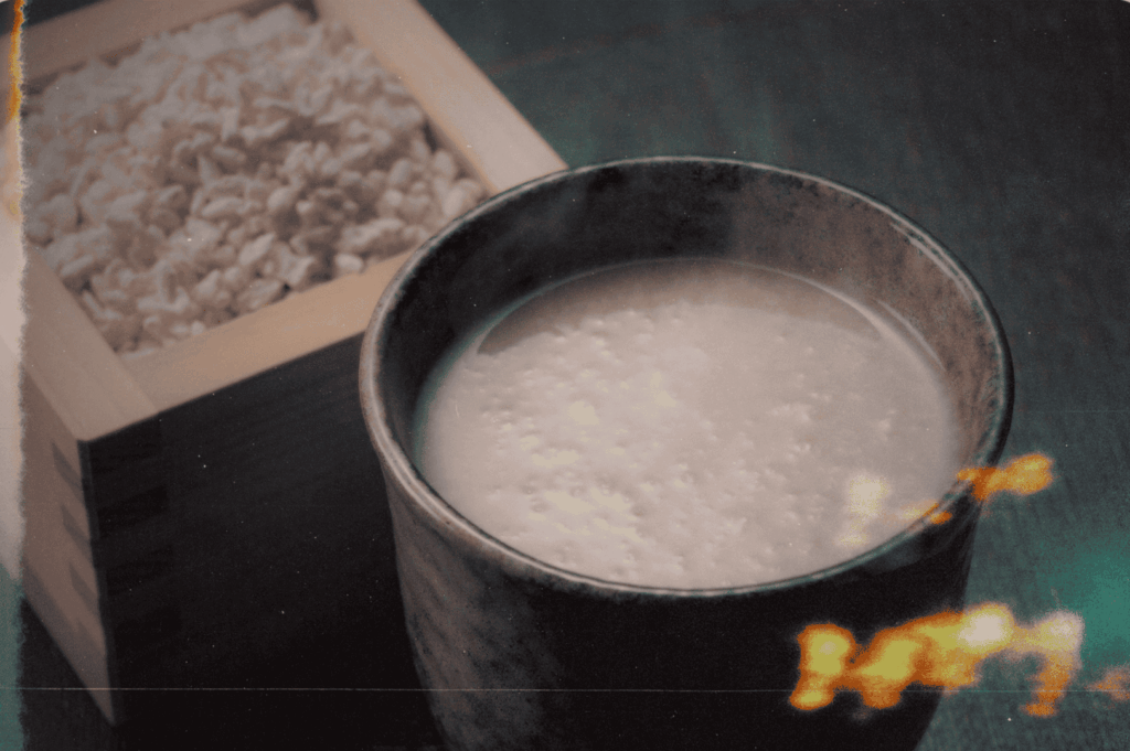 A ceramic cup of milky amazake sits beside a wooden box of rice, bathed in nostalgic light—embodying the quiet warmth and living memory of Japan’s fermented traditions.