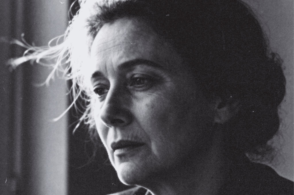 Black-and-white close-up of an older adult looking out a window, soft light on their face.