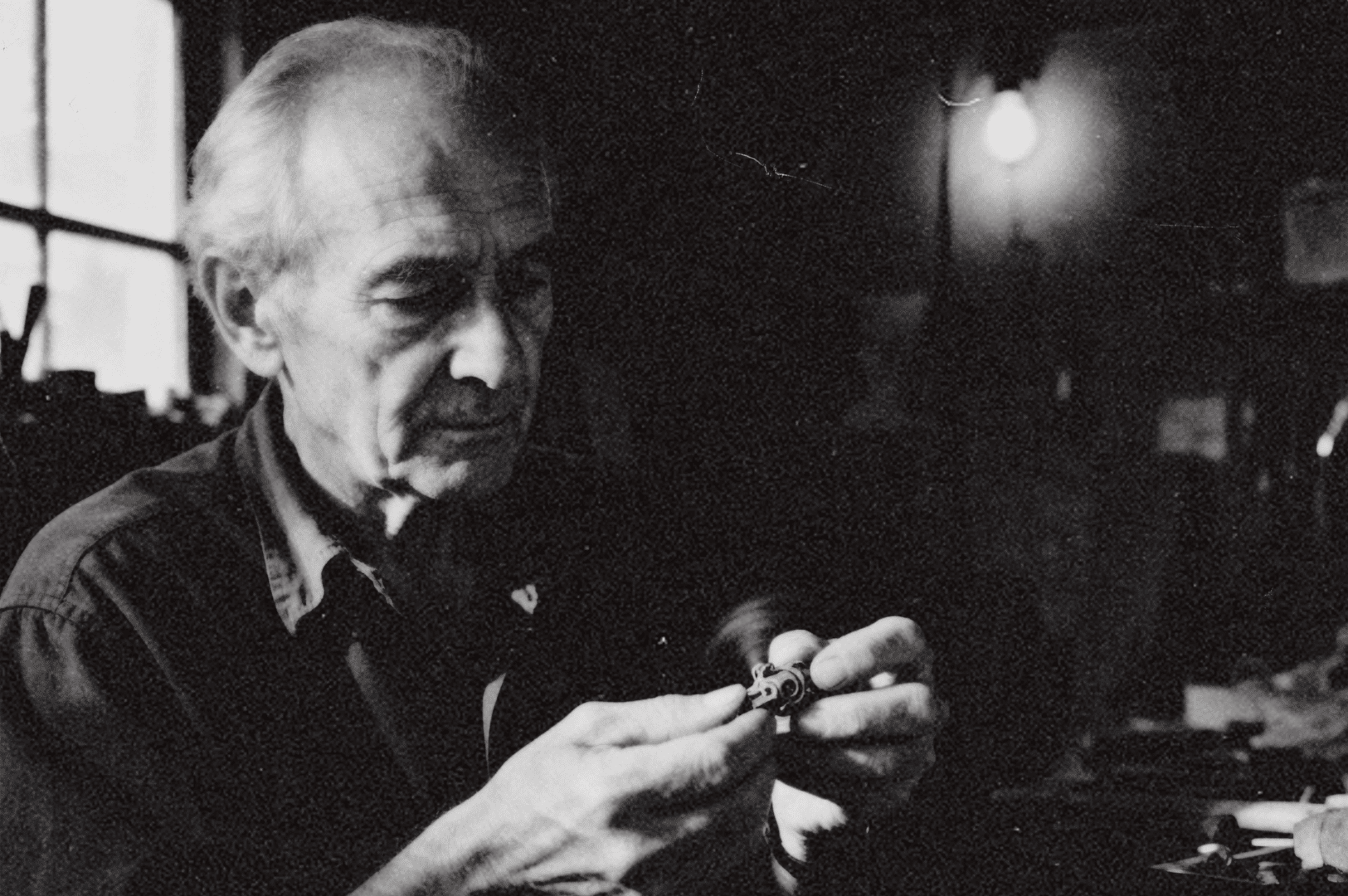 A lone tree stands on top of a grassy hill surrounded by light fog, with soft sunlight filtering through the mist.
