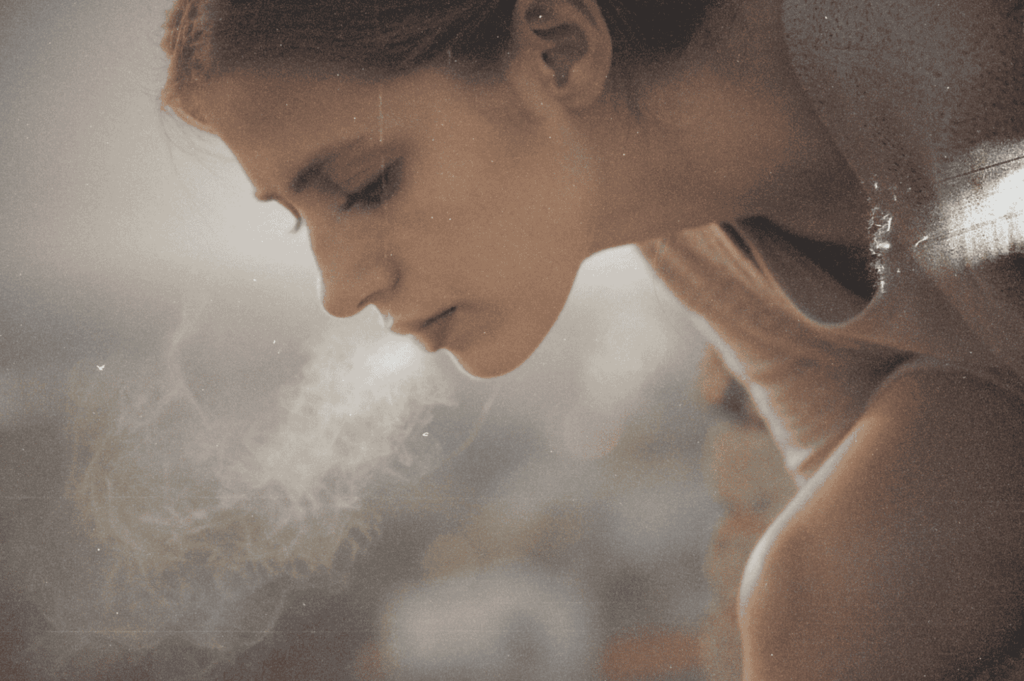 A side profile of a person exhaling visible breath into cold air—capturing the quiet intimacy of a moment suspended between inhale and release.