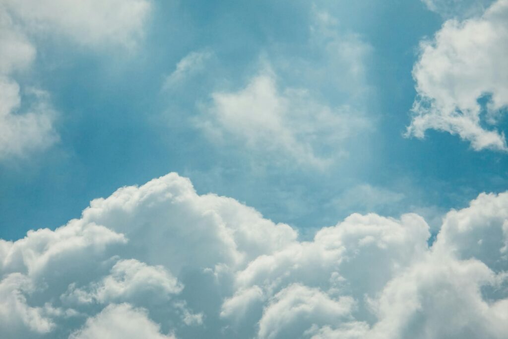This image captures a bright, turquoise-blue sky filled with various white cloud formations.