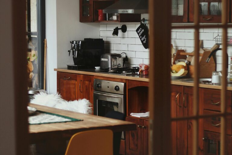 This warm, rustic kitchen features rich wood cabinetry and a white subway tile backsplash, accented by modern black appliances like an espresso machine and stovetop.
