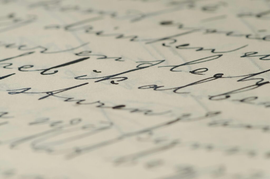 This macro photograph features a close-up view of elegant, cursive handwriting penned in dark ink on aged paper.