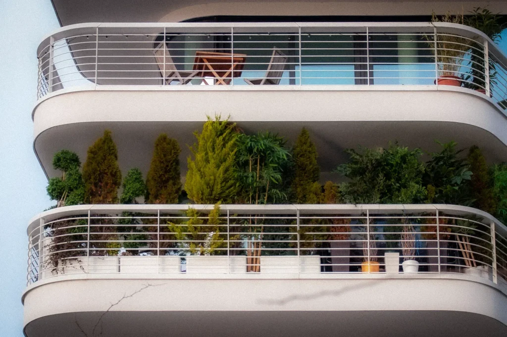 Modern apartment building balconies filled with potted plants and greenery, showcasing urban gardening, outdoor living spaces, and contemporary residential architecture.