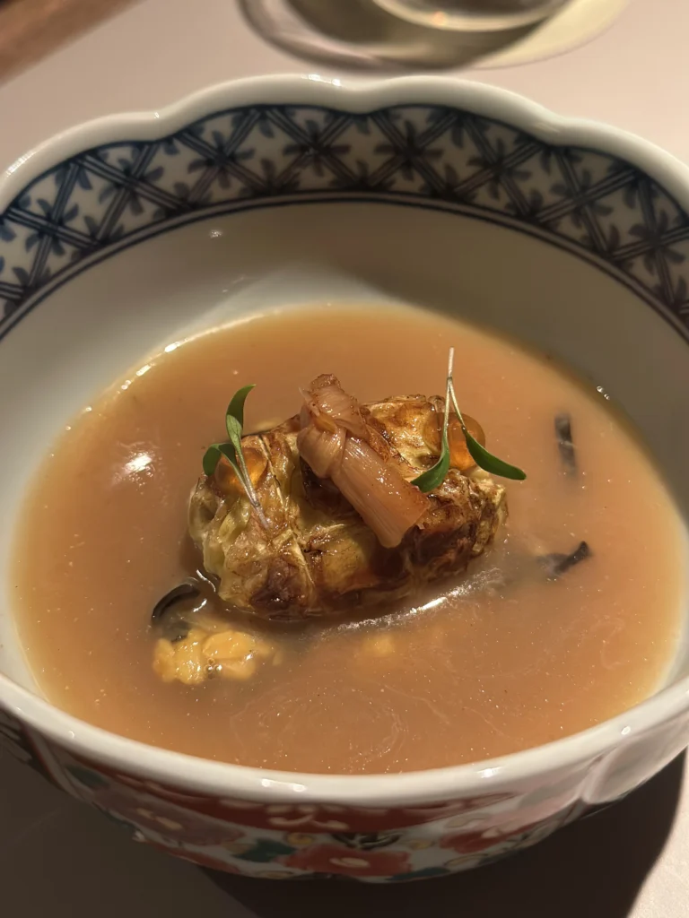 Gourmet broth dish with stuffed cabbage roll and herbs at Belimbing restaurant.