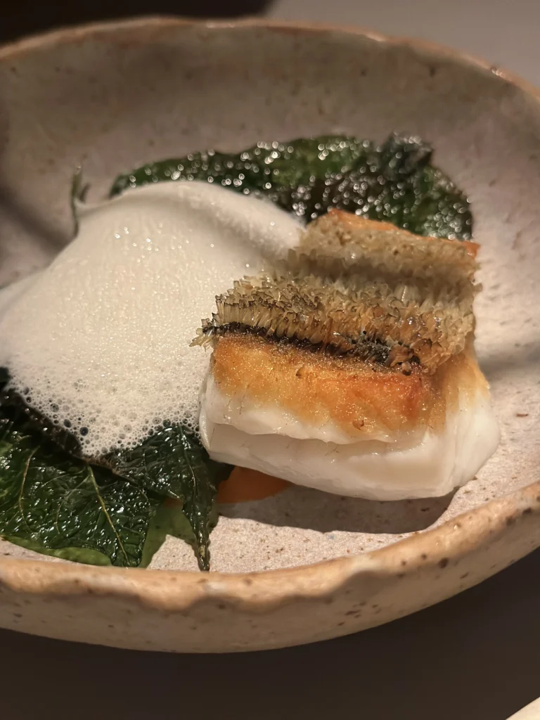 Crispy scale tilefish dish with culinary foam and green leaves at Belimbing restaurant.
