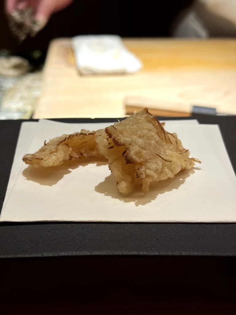 Maitake mushroom tempura with a light crispy batter, served fresh at a Japanese omakase counter.