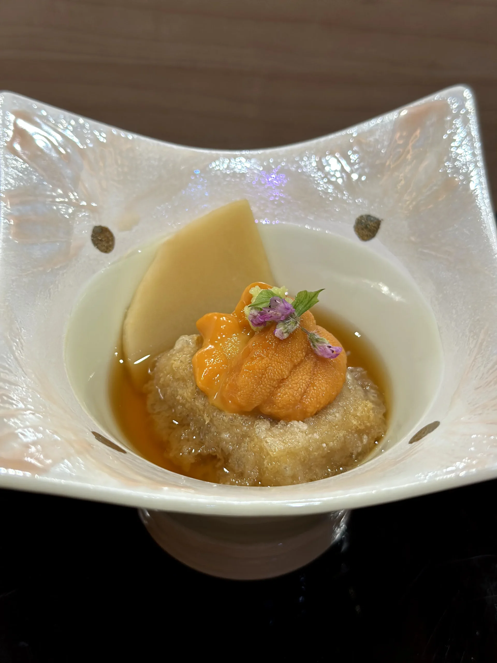 Delicate sea urchin and bamboo shoot appetizer served in a clear glass bowl with light savory broth