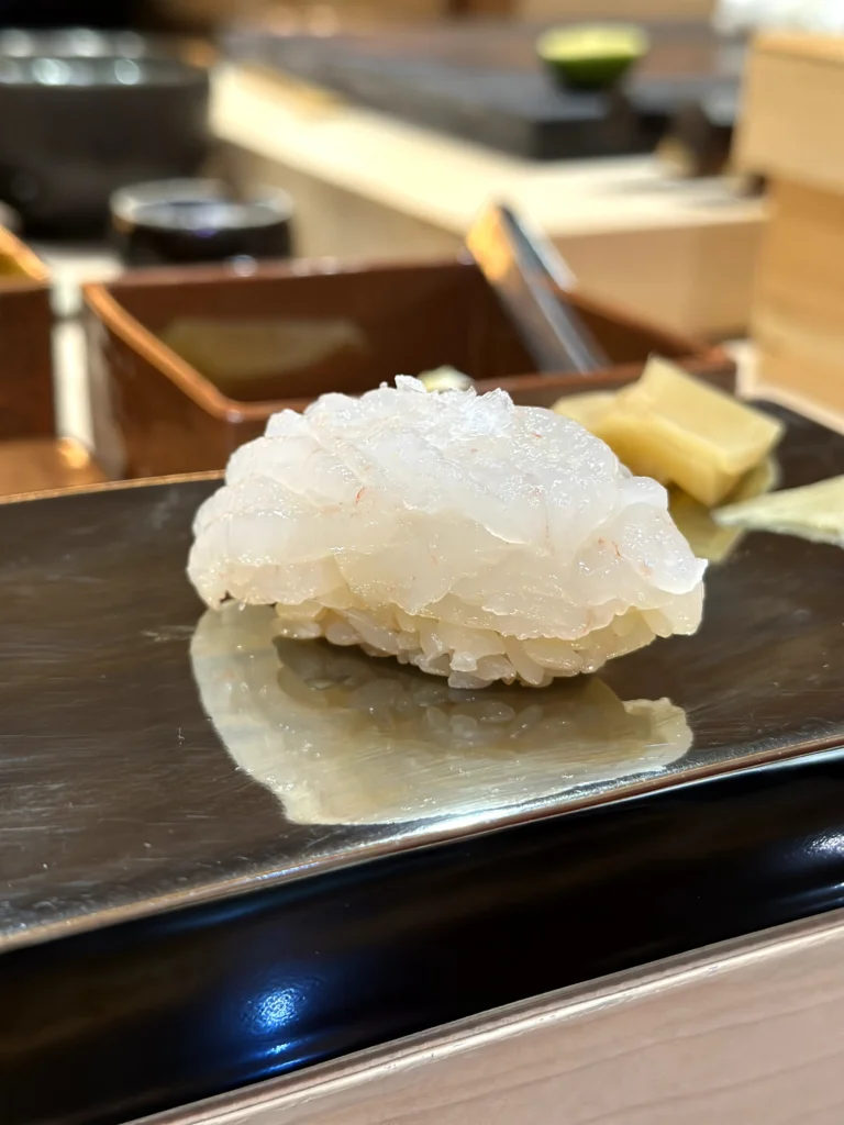 Fresh translucent white fish nigiri sushi served on seasoned rice with pickled ginger on the side