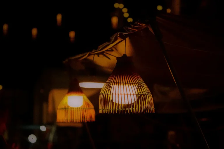 Warm glowing rattan lanterns hanging outdoors at night, creating a cozy ambiance with soft bokeh lights and a vibrant evening market atmosphere.
