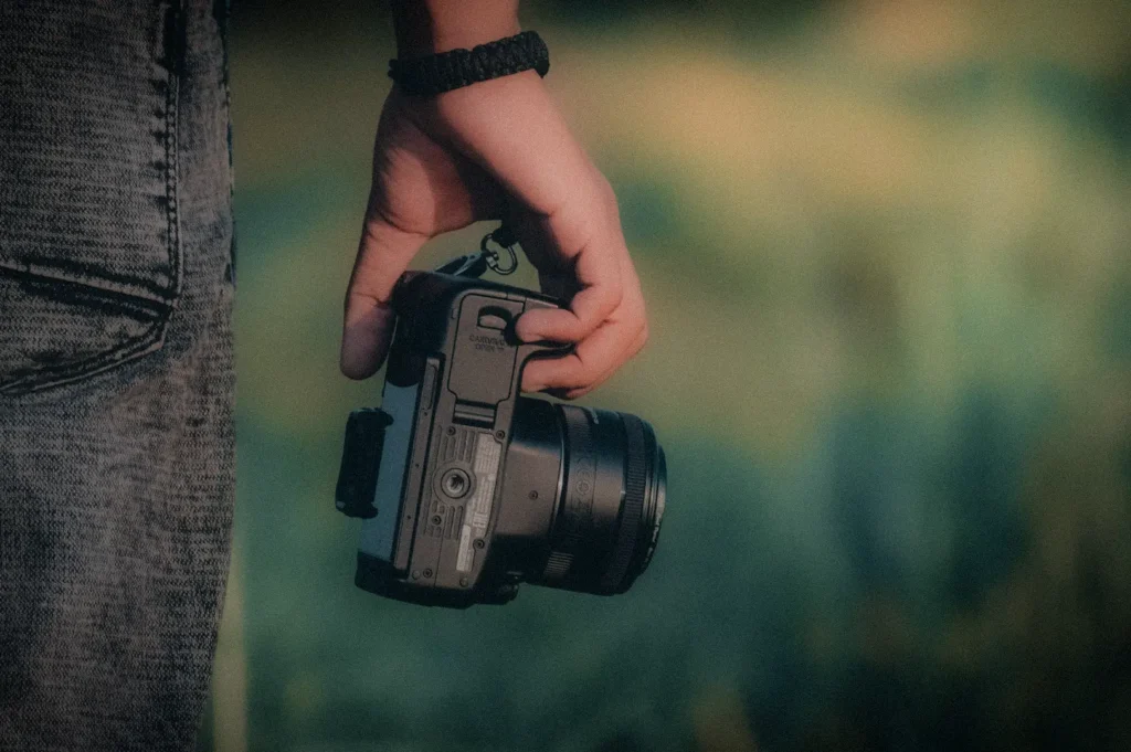 Close-up of a photographer holding a mirrorless camera outdoors, capturing the passion for photography, content creation, travel, and visual storytelling.
