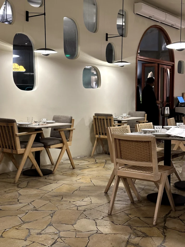 Modern interior of Bacio Italian Restaurant with minimalist décor, wooden furniture, arched windows, pendant lighting, and a warm, inviting dining atmosphere.