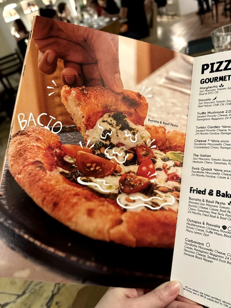 Restaurant menu featuring Bacio’s burrata and basil pesto pizza with a crispy, wood-fired crust and fresh cherry tomatoes, photographed in a cozy Italian dining setting.