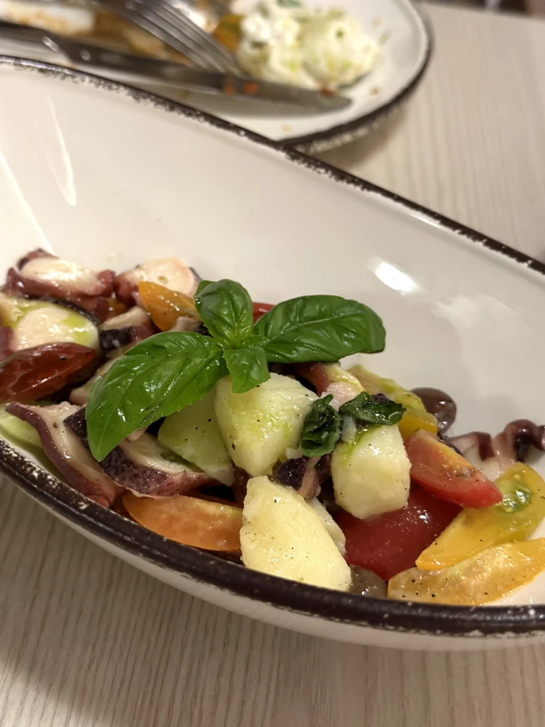 Mediterranean octopus salad with baby potatoes, cherry tomatoes, fresh basil, olives, and olive oil served at Bacio Italian Restaurant.